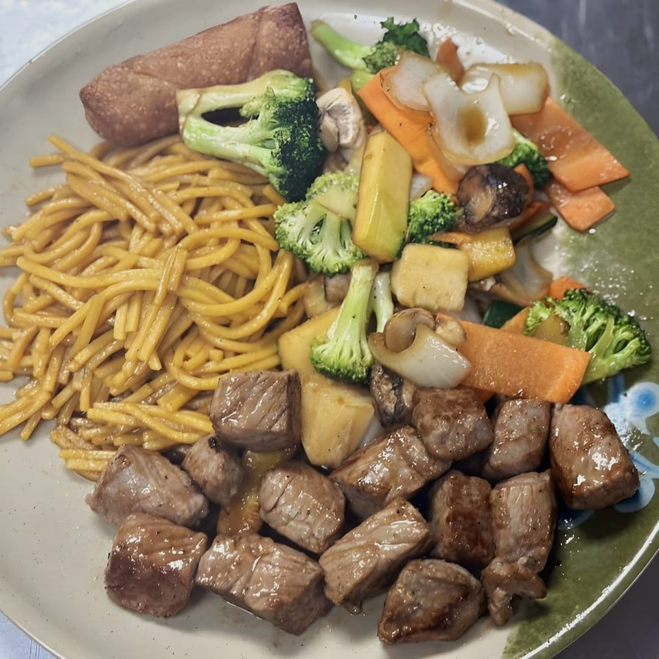 A plate of Hong Kong Palace Asian Restaurant's Asian-fusion meal with noodles, mixed vegetables, and beef.